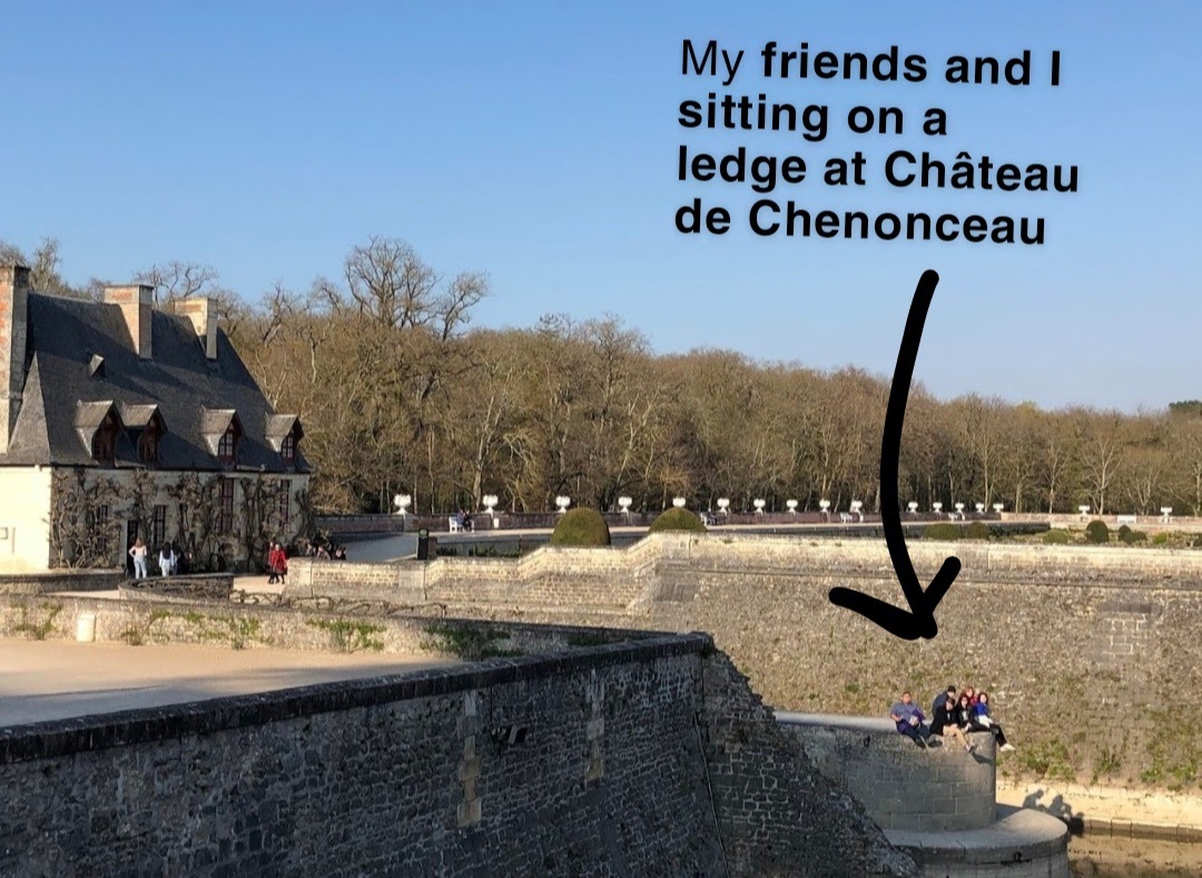Lars and their friends sitting on a ledge at Château de Chenonceau
