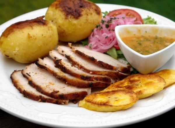 a white plate with potatoes, meat, a salad and ají