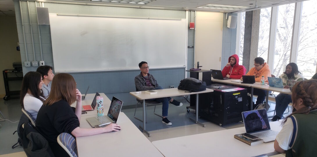 Instructor and students at a class meeting in GH 207. The front whiteboard is visible.