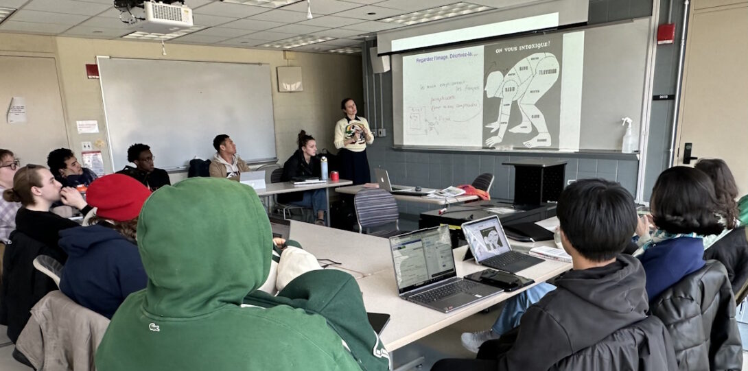 Instructor and students at a class meeting in GH 207. The instructor is using a presentation slide, which is visible on the front whiteboard.