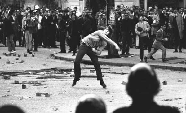 student throwing rock while crowds watch